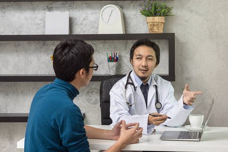 亚洲男医生在现代医院办公室使用技术笔记本电脑与患者讨论健康诊图片