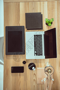 办公室木制桌面上有图形平板电脑和智能手机的笔记本图片