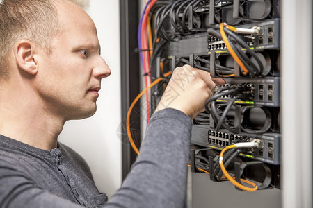 信息技术工程师或技术员从事网络电缆布线和在数据中心安装通信开关的工作单图片