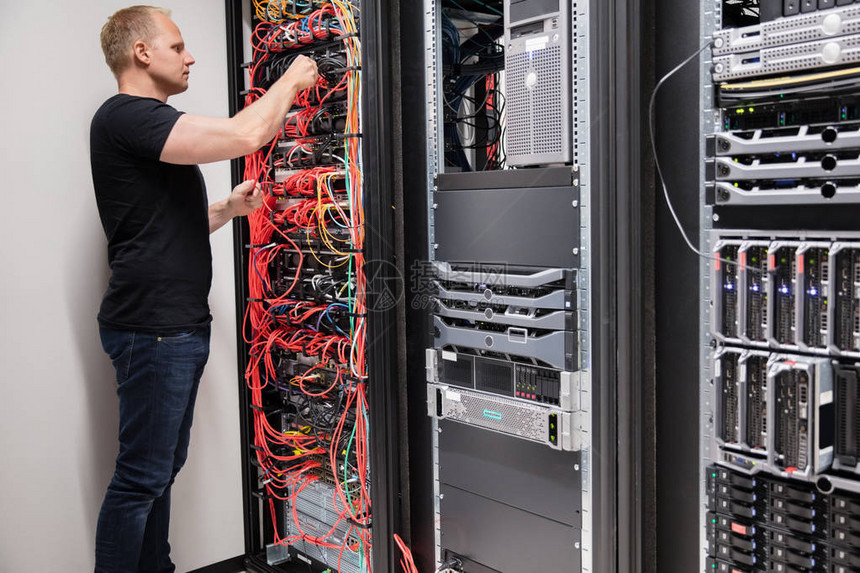 中年男IT技术人员检查连接到数据中心服务器的网络图片