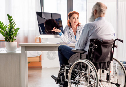 美丽的女医生向坐轮椅的高级病人图片