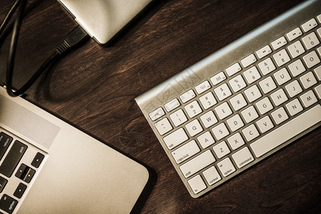 企业家办公桌现代办公桌笔记本电脑无线键盘和便携式外置驱动器深色木制图片