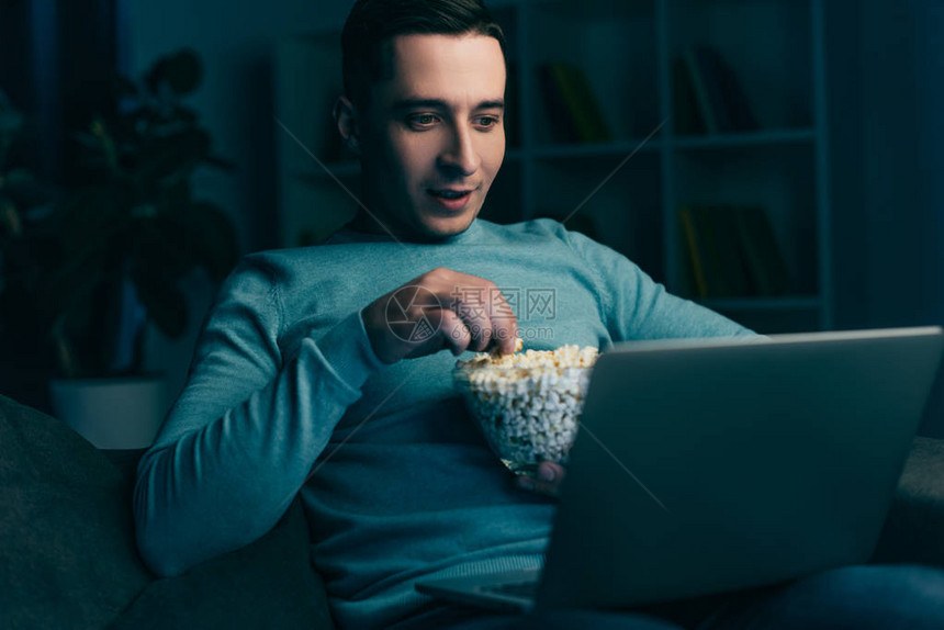 帅男人在笔记本电脑上看电影在家里拿图片