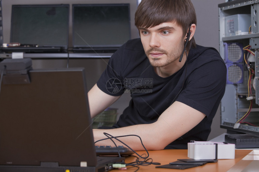 男程序员手持提笔记本电脑耳机图片