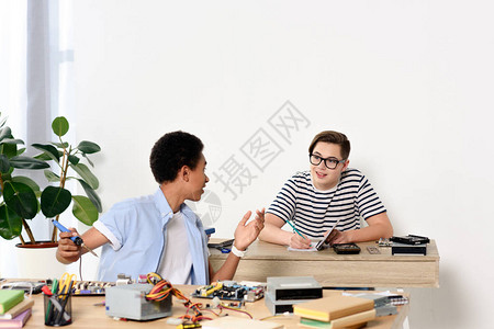 在家里修电脑主板的多元文化青少年交谈图片