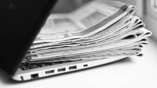 报纸和笔记本电脑个人电脑和一堆带有新闻的日报屏幕或纸上的信息新鲜的数据老式的期刊和现代技术业务来源背景图片