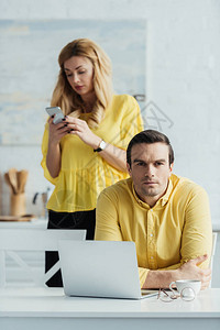 男人坐在桌边用笔记本电脑在妇女面前图片