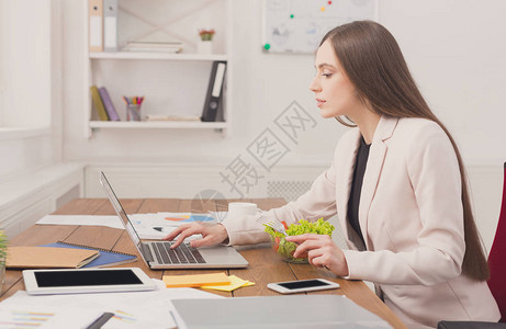 在办公室用笔记本电脑工作的商界女强人女商人坐在工作地点在电脑上打图片