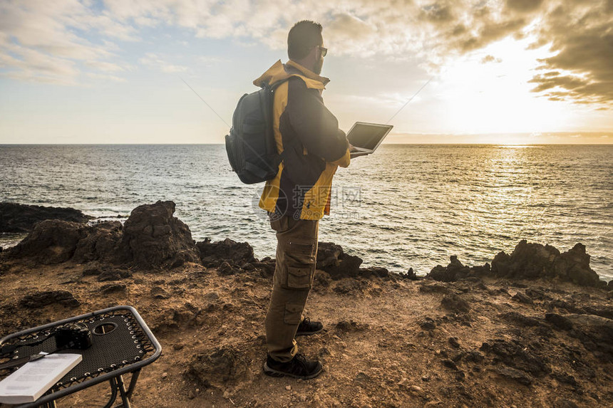 数字游牧旅行者在工作中寻找海洋上令人惊叹的日落相机和笔记本电脑以及户外休闲活动中的美好生活方式替代工作办图片