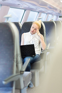 商业女商人在火车上和笔记本电脑工作时坐着打盹睡觉图片