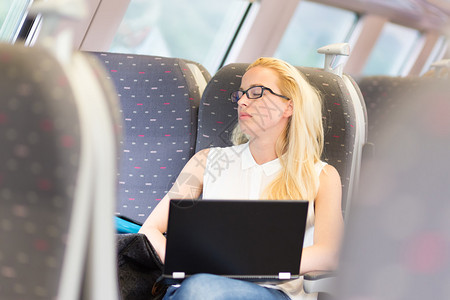 商业女商人在火车上和笔记本电脑工作时坐着打盹睡觉图片