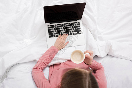 膝上型笔记本电脑和咖啡坐在床上背景图片