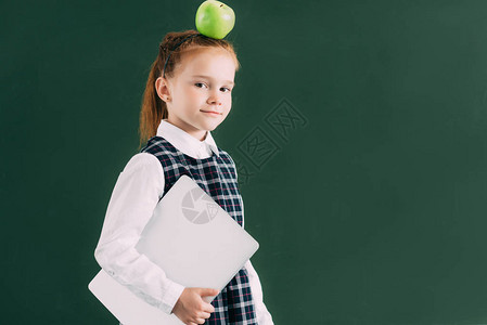 带着苹果的漂亮小女学生头顶拿着笔记本图片