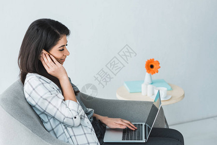 女孩坐在椅子上在笔记本电脑工作时图片