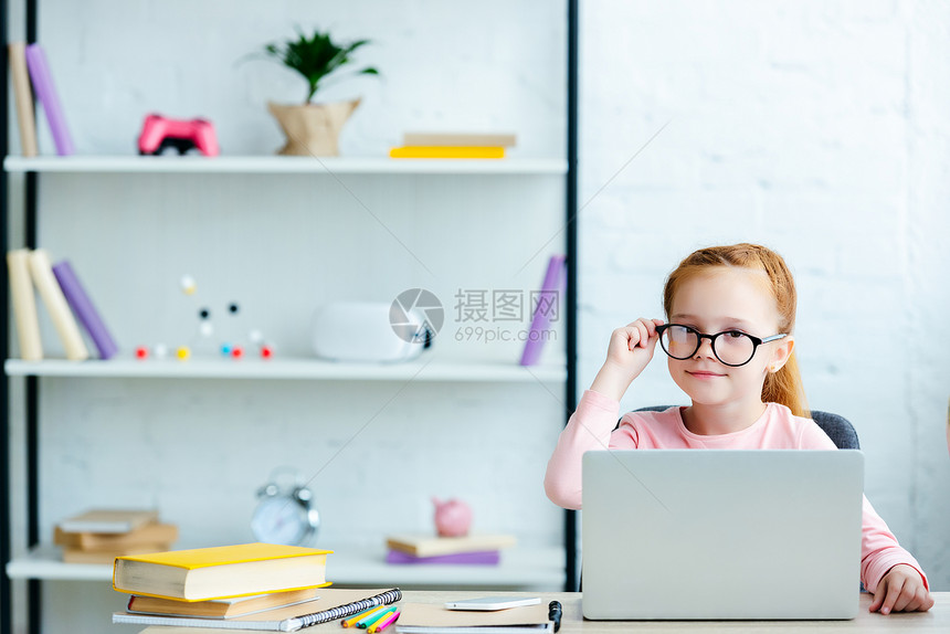 带着笔记本电脑和在家中学习时对镜头微笑的眼镜中可爱的红图片