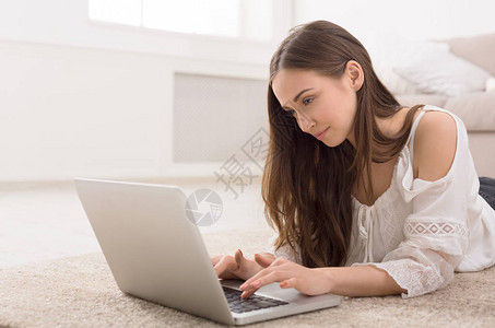 快乐的浪漫女孩在笔记本电脑上聊天时躺图片