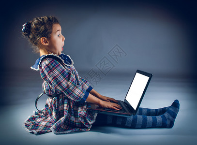 坐在地上玩笔记本电脑的少女在灰色背景十字过图片