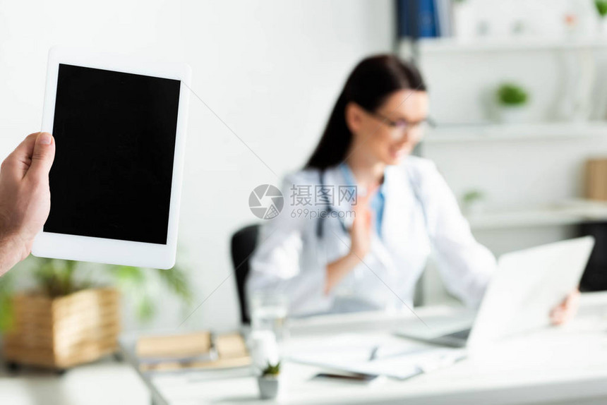 男子在诊所办公室持有数字片面空白屏幕的人与医生通过笔记本图片