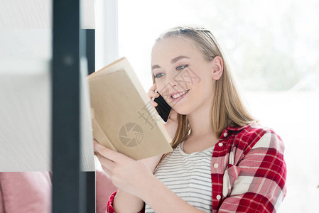 微笑着的少女学生女孩阅读书和电话交谈图片