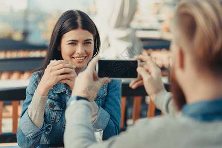 男人用智能手机在咖啡厅户外用智能手机拍摄快图片