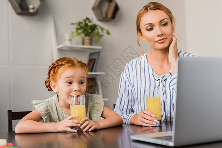 母女俩喝橙汁看着笔记本电脑图片