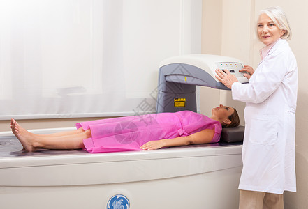 在专业援助下进行X光扫描的女图片