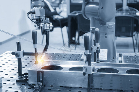 用于在浅蓝色场景中焊接汽车零件的焊接机器人现代制造工艺的工业图片