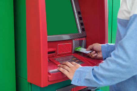 男手使用和插入ATM卡到银行机器取款图片