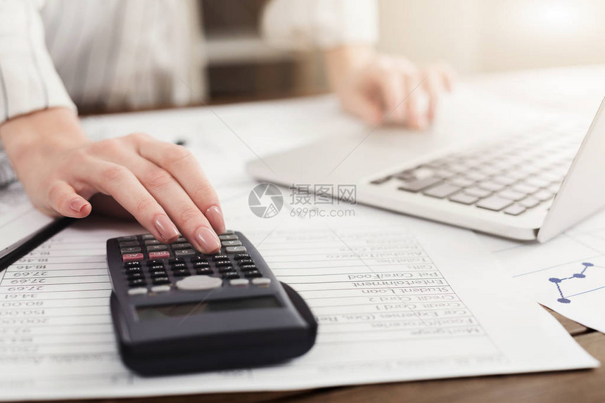 年轻女管理财务审查笔记本电脑和计算器的银行账户在线纳税复图片