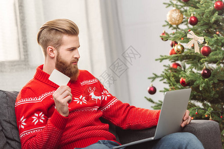 持有信用卡和使用笔记本电脑在圣诞节网上购物时使用笔记本的英图片