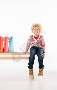 小孩坐在长椅上带着白色孤立的丰富图片