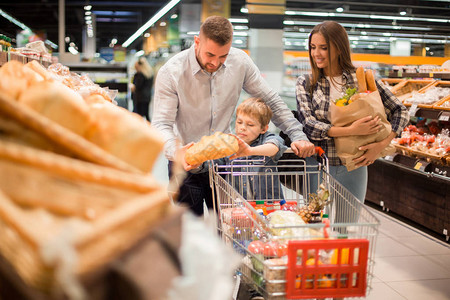 喜悦的年轻家庭购物在超市与小男孩一起购买杂货图片