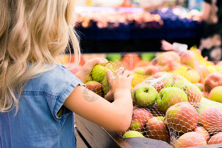 女孩子在超市挑选苹果的背影背景图片