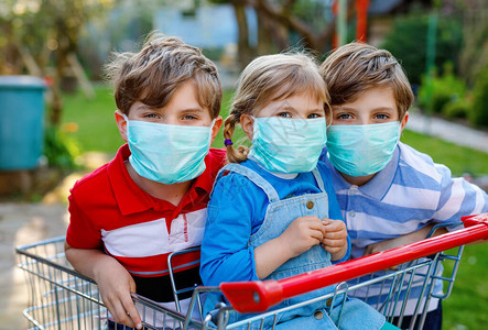 三个孩子蹒跚学步的小女孩和两个戴着医用口罩的男孩图片