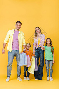 快乐的父母与子女牵手同时在黄色上持有图片