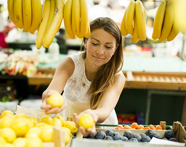 漂亮的年轻女人在市场上买水果图片
