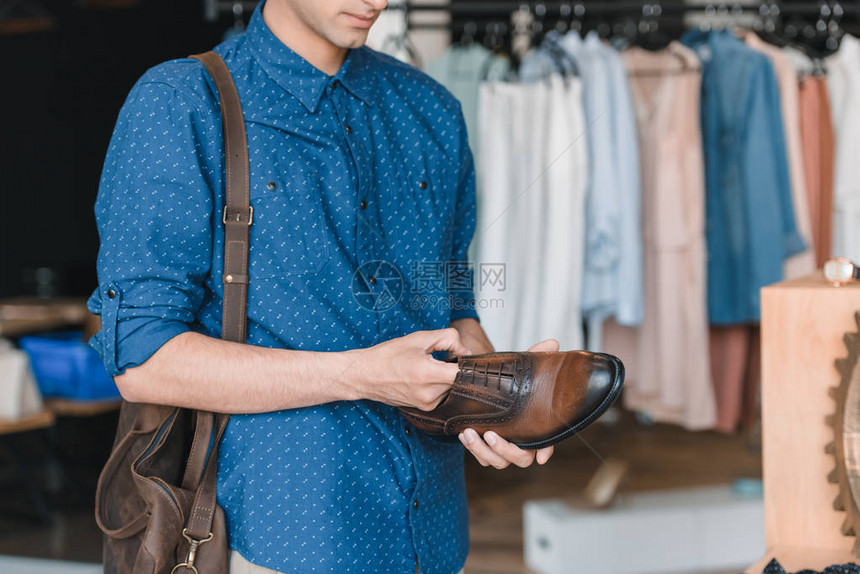 青年男子在商店购物时拿着鞋的图片