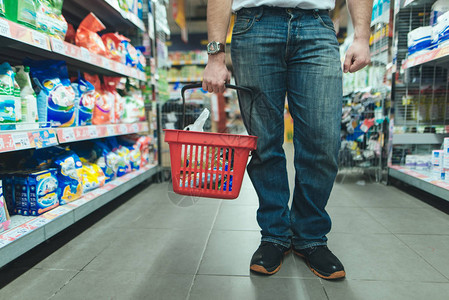 一个在超市买东西的人腿和一个红色的购物袋选择市场上的产品图片