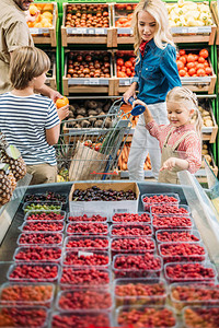 有两个孩子在超市选择浆果的年轻家庭微笑图片