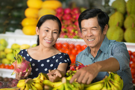 关于一对老年夫妇在前台市场购买水果和蔬菜的近视图片