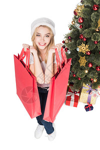 戴着圣诞老人帽子带着购物袋的微笑女人的高视角图片