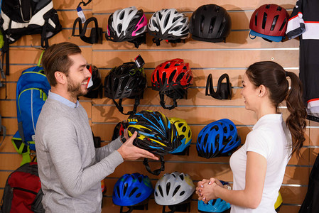 在自行车店选择自行车头盔时卖家和顾客互图片