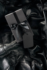 黑皮夹克背景上贴着空白价格标签的黑包礼物背景图片