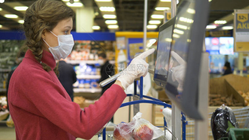 戴着医用口罩和橡胶手套的女人在超市里用电子秤称苹果科罗纳威斯大流行保护背景是戴着防图片
