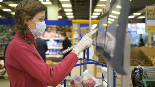 提高免疫力科普戴着医用口罩和橡胶手套的女人在超市里用电子秤称苹果科罗纳威斯大流行保护背景是戴着防背景
