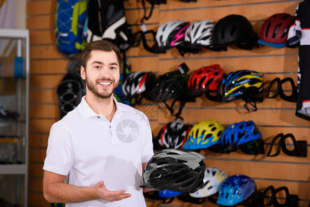 男青年工人持有自行车头盔在自行车店的图片