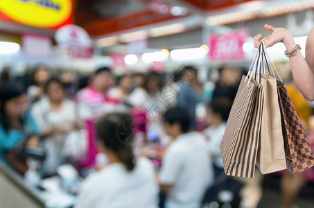 在摘要模糊的出纳店面照片上手持商店袋图片