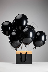 黑色的黑气球和纸购物袋在灰色黑色的星期五图片