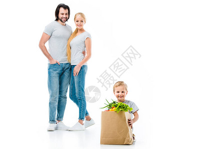 小男孩带着杂货袋和他父母站在后面图片