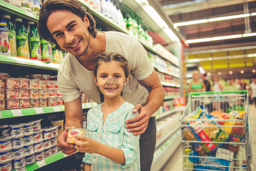 英俊的年轻父亲和可爱的小女儿在超市中选择食物时图片